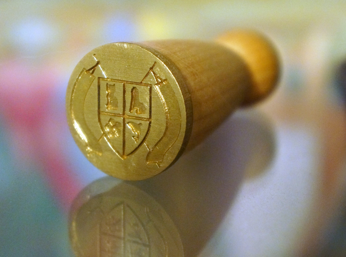 The raw brass stamp attached to it's wooden handle.