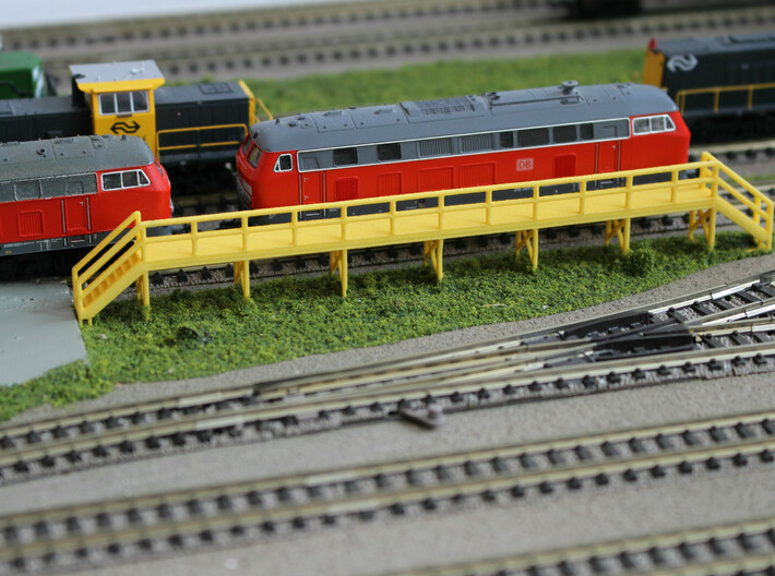 N Scale Train Maintenance Platform DOUBLE STAIRS 3d printed Train maintenance platform with two stairs in Yellow Strong &amp; Flexible Polished, unpainted. The base is covered in grass.