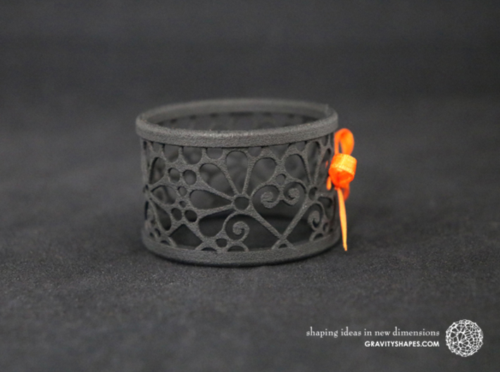 A large napkin ring with Mosaic-3b 3d printed The photo shows a print made of black strong and flexible incl. orange lacing.
